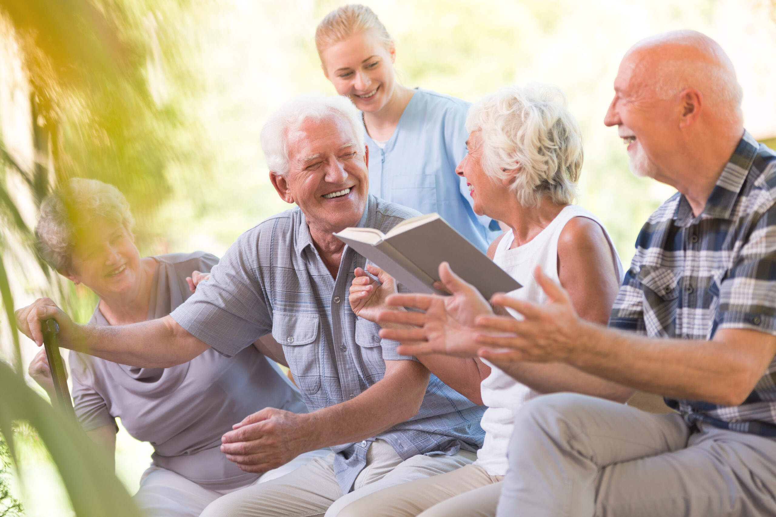 Happy Seniors from Nursing House Spending Day Outside and Reading Book Together